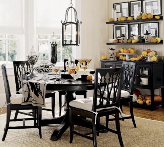 a stylish vintage black and white Halloween table setting with printed textiles, spiders, black and white candies and fresh cocktails
