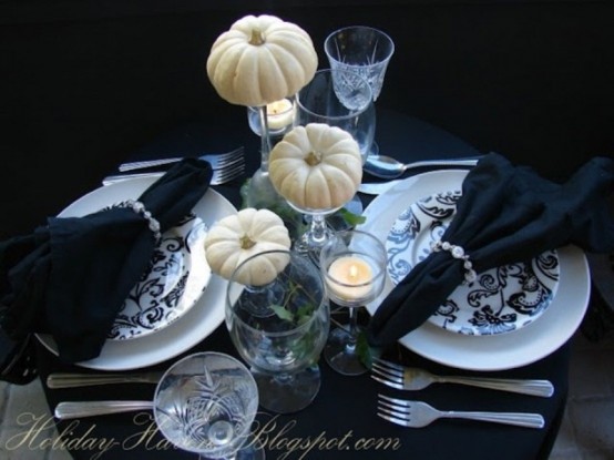 an elegant modern black and white Halloween tablescape with printed plates, black linens, white pumpkins and candles