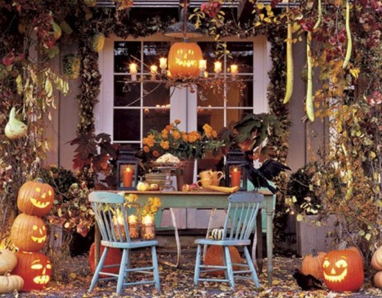 rustic Halloween table decor done with candle lanterns, crows, pumpkins and jack-o-lanterns, fall leaves and lights