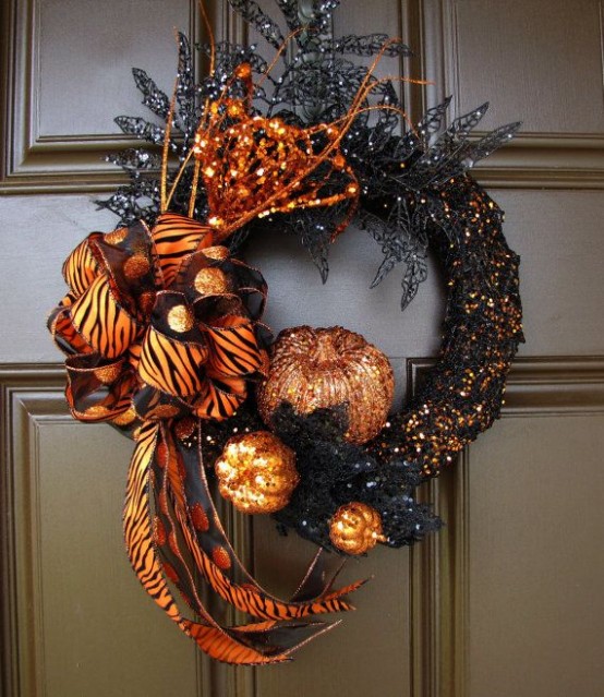 a sophisticated black and orange glitter Halloween wreath with glitter leaves, pumpkins, an oversized orange printed bow and some twigs is a very cool and fresh idea
