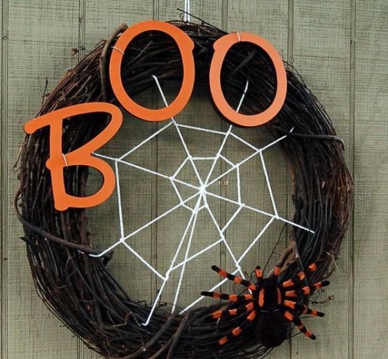 a stylish Halloween wreath of vine,w ith orange letters, a spider net and a large and bold spider is a geat idea for Halloween