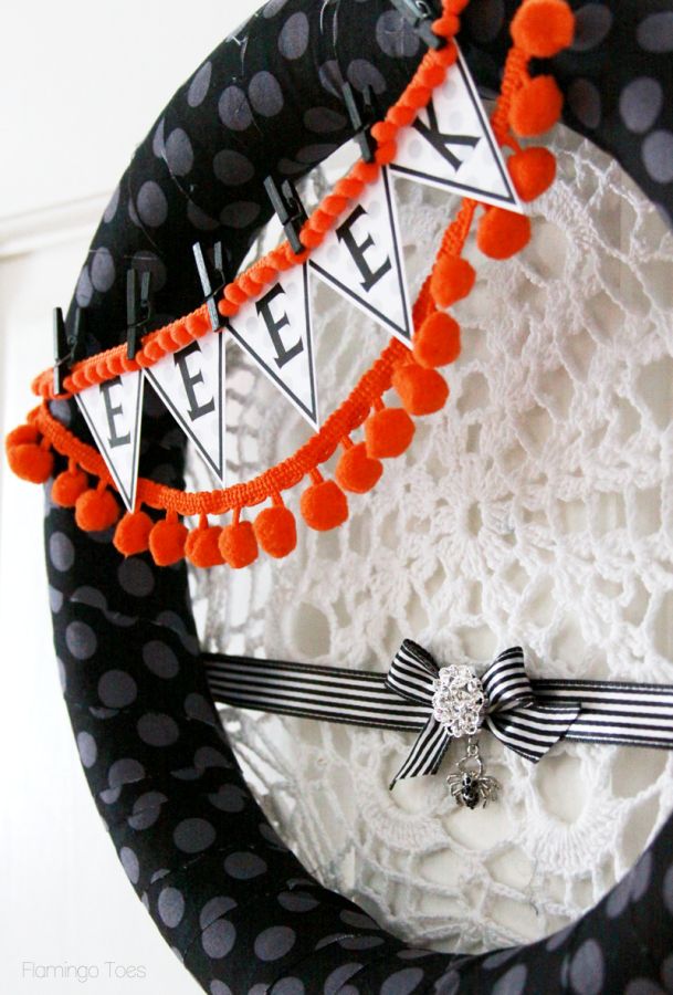 a black polka dot Halloween wreath with a bunting and orange pompoms, a doily spider net and a stripe ribbon with a bow and a spider pendant is a lovely idea to rock