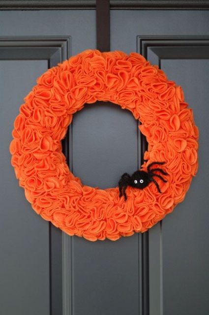 an orange fabric wreath with a black spider is a colorful and pretty decoration for Halloween you can easily make