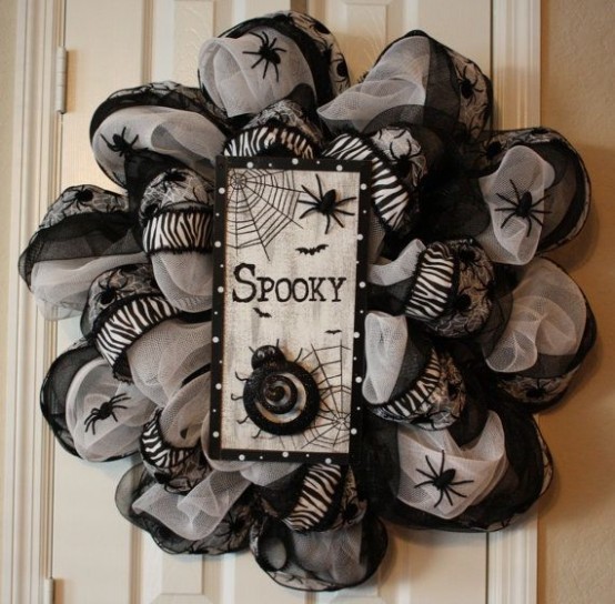 a whimsy black and white Halloween wreath covered with fabric and ribbons, with spiders and a sign with spider nets and spiders is a unique solution for decor