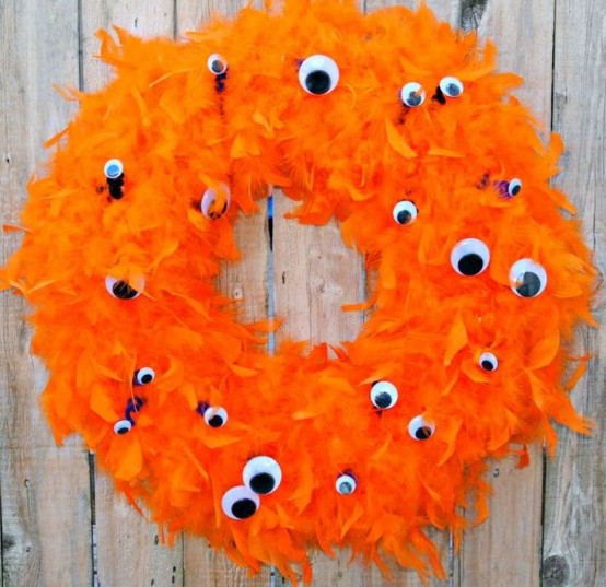 a bold orange feather wreath with googly eyes all over is a lovely and bright idea for Halloween decor