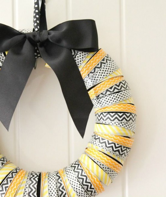a bright Halloween wreath covered with printed black, white and yellow ribbons and a large black bow on top is a gorgeous idea