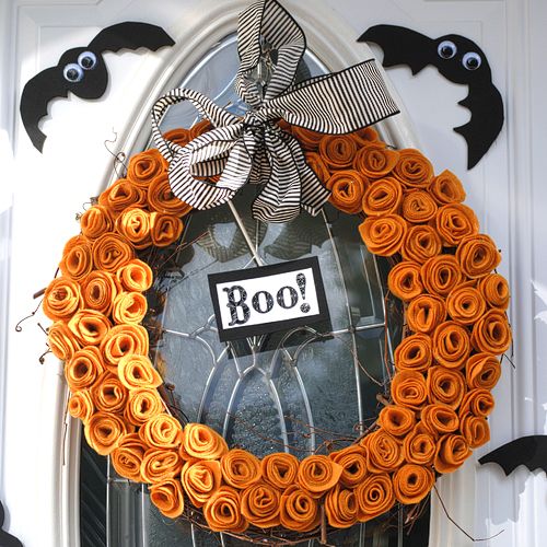 a bright and cool Halloween wreath of orange fabric swirls shaping a pumpkin, a striped bow, a sign and some faux bats around is amazing