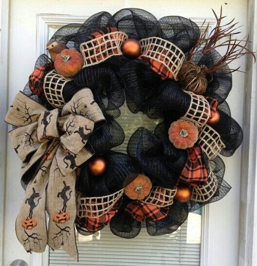 a bold and catchy Halloween wreath of shiny black ribbon, mesh ribbon, a printed bow, glitter mini pumpkins and rust ornaments is amazing