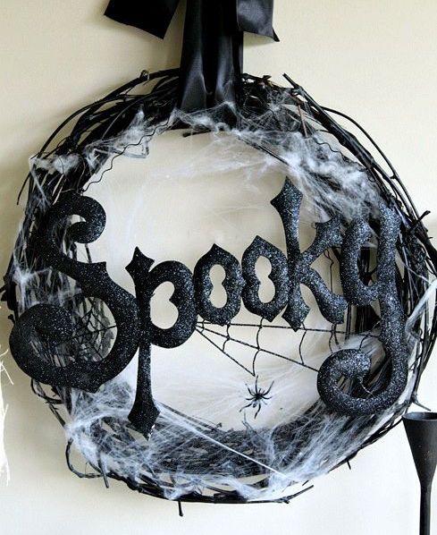 a bold black Halloween wreath of vine, with shiny and sparkly letters, spider net and a large bow on top is a stylish and cool idea