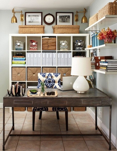 a neutral rustic home office with open shelves, an open storage unit, a dark-stained desk, a black chair and cool decor