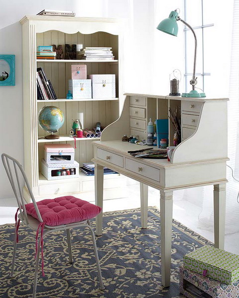 an eclectic space with a large vintage bookcase, a matching ivory bureau desk, a chair with a pink cushion, blue and green touches