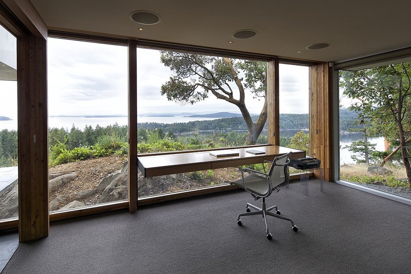 a gorgeous home office with glass walls that allow you enjoying all the views, a floating desk and a chair   you won't need more in this amazing space