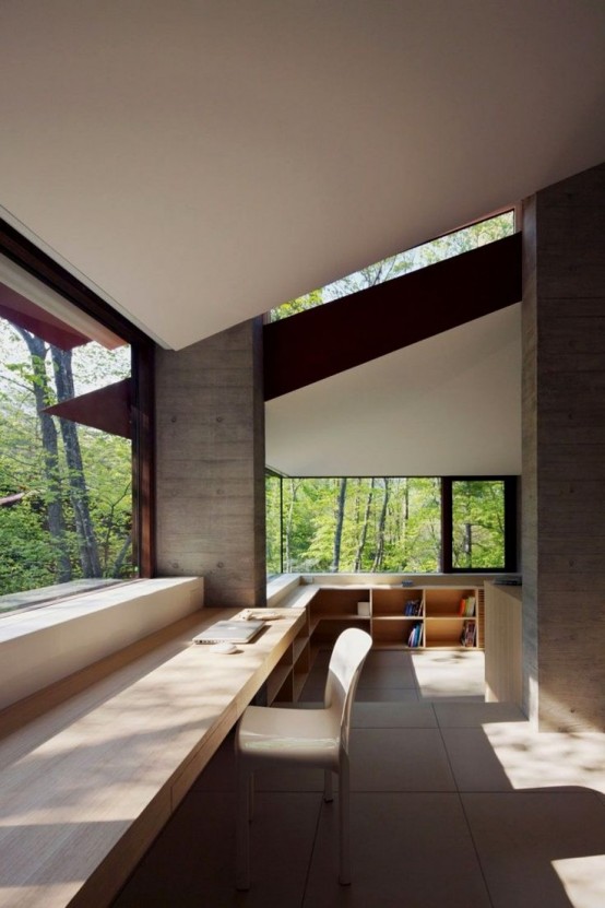 an ultra-minimalist home office with extensive glazing, a shared desk, some storage units and a chair and lovely views of greenery outside