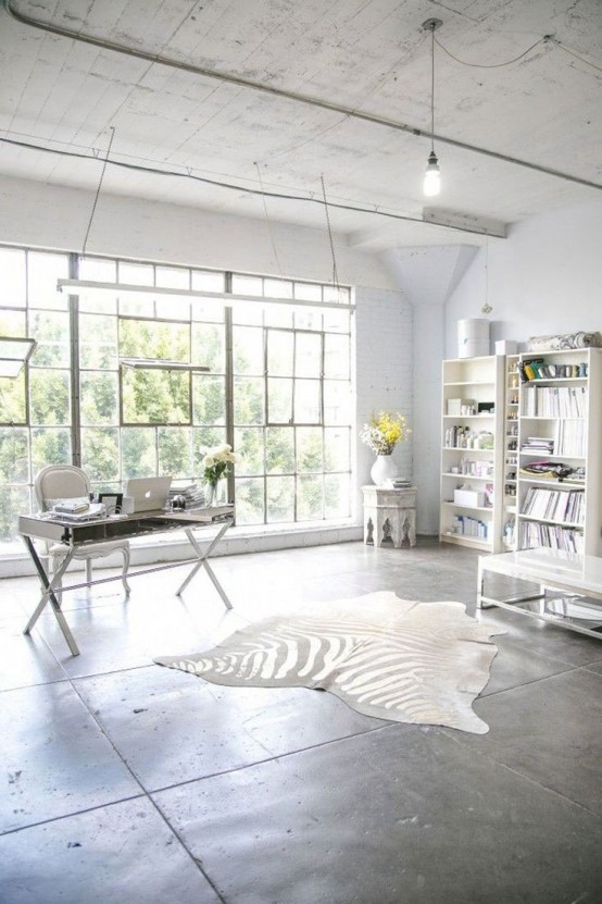 a white home office with a glazed wall, a white desk and a chair, white bookcases, a zebra-printed rug and a glazed wall with a garden view