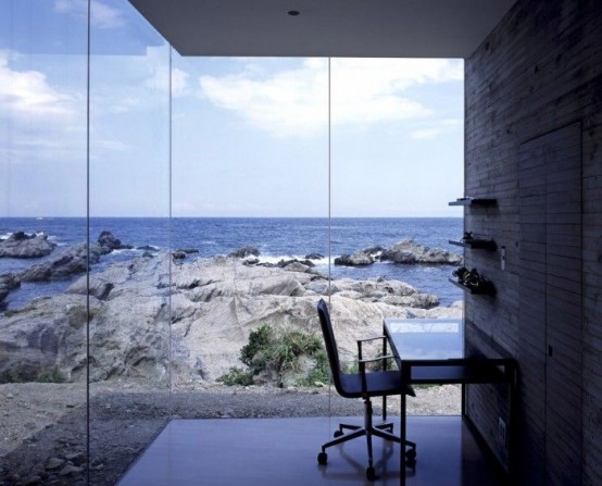 a beautiful small home office with glazed walls, a wall-mounted desk and a chair and jaw-dropping views of the sea that take the central place here