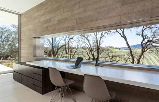 a modern neutral home office with an accent wall, a long and narrow window to enjoy the views and a long shared desk plus a couple of chairs
