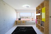a modern home office with a large storage unit, a window with a view of the city, a shared desk with chairs and a fun black rug
