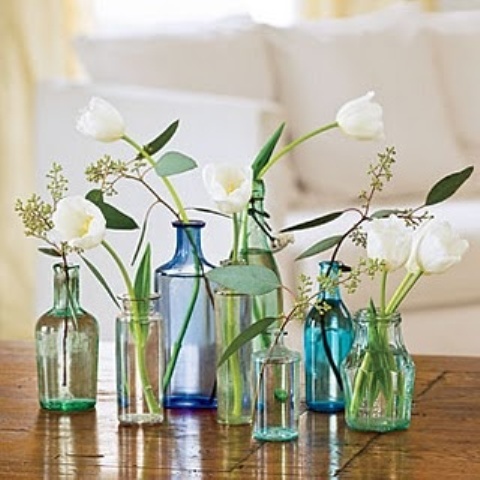 an arrangement of green and blue bottles with white blooms is a stylish decoration or a centerpiece for any space, with just a bit of color