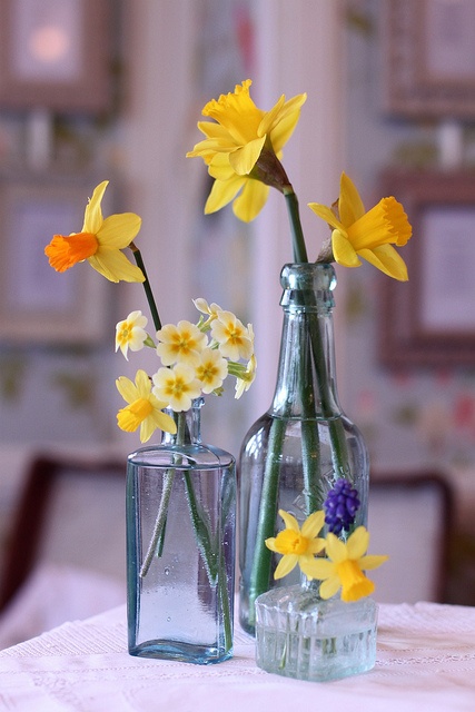 an arrangement of blue vintage bottles with bright spring blooms is a cool idea to decorate a space for spring, they look cool and spectacular