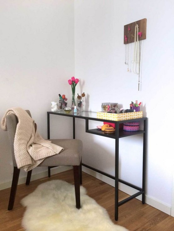 a pretty makeup nook with a black Vittsjo table as a vanity, with lots of makeup, accessories and other stuff and a grey chair