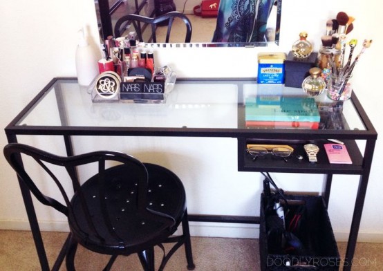 a black Vittsjo table as a vanity, with makeup and a mirror, a crate for storage under it and a vintage black chair