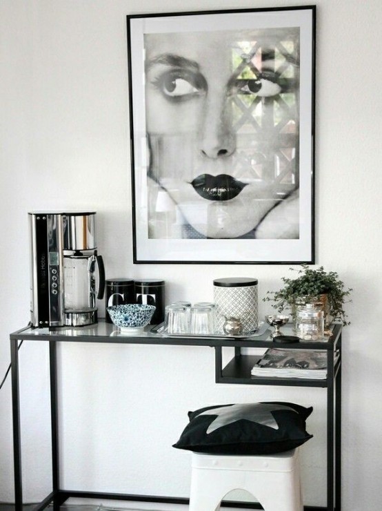 a black and white space, a Vittsjo table used as a home bar and a console table, with plants, a coffee maker and an artwork and a stool