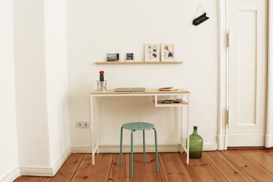 a small working nook with an IKEA Vittsjo table as a desk, a ledge with posters, a blue stool and a large green bottle is cool