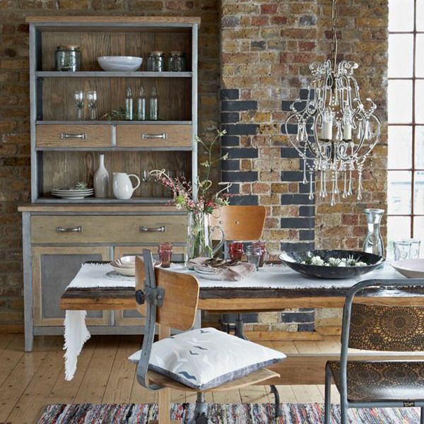 a vintage industrial dining space with a chic buffet, a reclaimed wood table, metal and wood chairs, a crystal chandelier