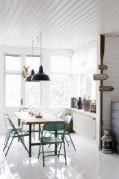 a Scandi industrial dining space in white, with a minimal industrial table, green metal chairs, black metal pendant lamps is cool and welcoming