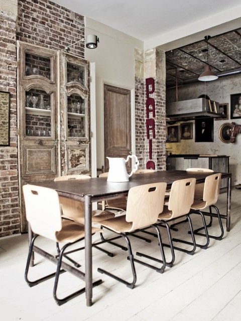 an industrial dining room with brick walls and a built-in storage unit, a metal dining table and timber and metal dining chairs, letters on the wall