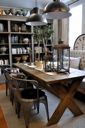a rustic industrial dining space with a stained trestle table, metal chairs, a chic loveseat and metal pendant lamps, elegant lanterns and greenery
