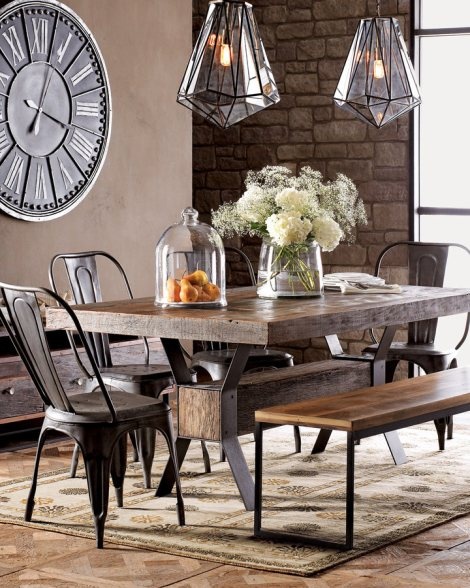 an industrial dining room with a rough wood industrial table, metal chairs, a bench and faceted pendant lamps plus an industrial clock on the wall