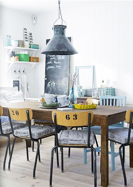 a lovely industrial dining space with a stained dining table, industrial chairs with numbers, a metal pendant lamp and some willow in a vase