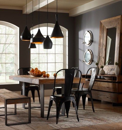 a modern industrial dining room with a rough wood and metal table, metal chairs, a cluster of black and gold pendant lamps is a lovely and chic space to have meals