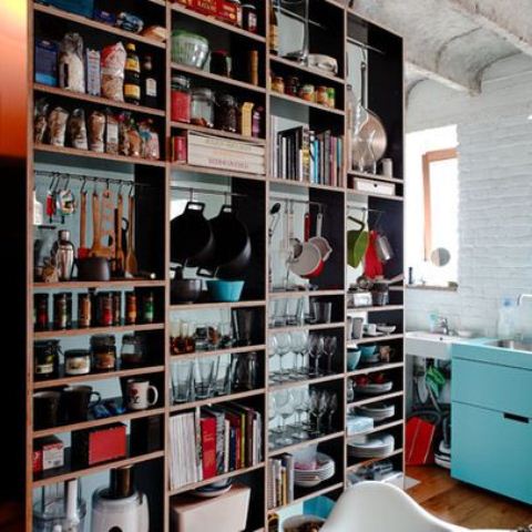 an oversized open shelving unit is used to separate the spaces and hold everything the owners may need, it's a great idea