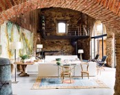 a vintage living room with a double height ceiling and original brick walls and touches of stone