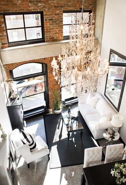 a small contemporary living room in black and white, with a statement brick wall and a crystal chandelier