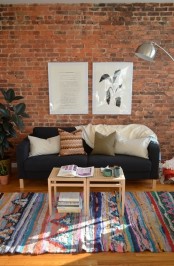 a bright boho living room with a red brick wall that adds texture and interest to the space