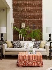 an eclectic living room with a dark brick statement wall that contrasts the white surfaces