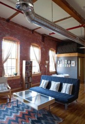 an industrial living room done with red brick walls and metal pipes on the ceiling plus mid-century modern furniture