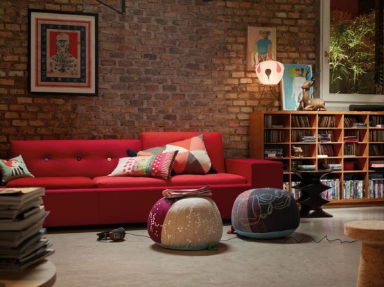 a bright contemporary living room with a red brick wall and vibrant furniture and artworks