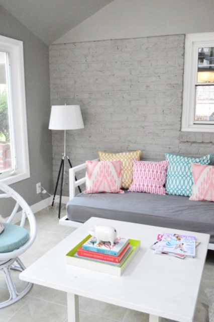 a chic neutral space with a grey brick accent wall and pastel touches and furniture
