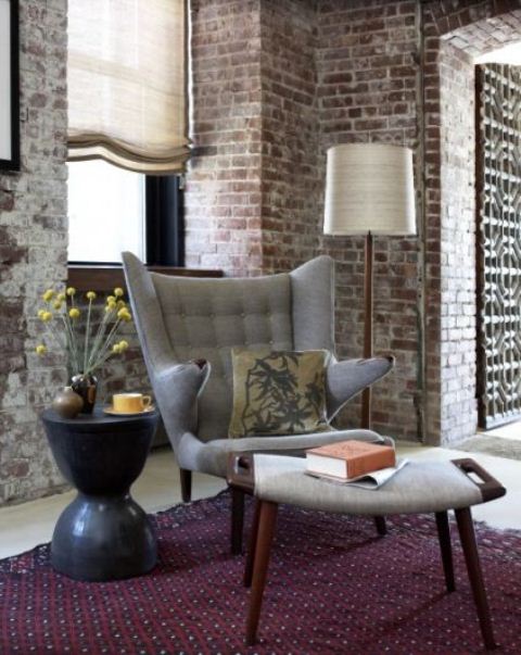 a chic living room with red brick walls and white grout, contemporary furniture and Roman shades