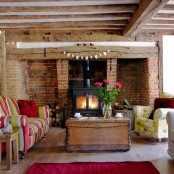 a rustic living room with a red brick wall and much wood in decor, with colorful upholstery furniture