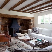 a refined and chic living room in neutrals and spruced up with a black hearth and a red brick statement wall
