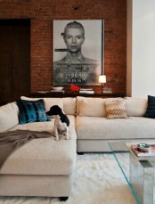 a contemporary living room with neutral upholstered furniture and a red brick statement wall that contrasts