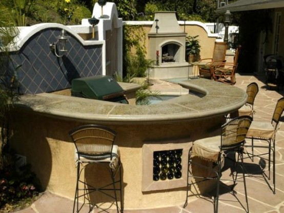 a comfortable dining area built of stone, with a stoen countertop and a grill inside it plus a hearth next to it
