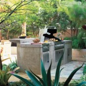 an outdoor kitchen with concrete and metal with a grill and a raised top for having a meal