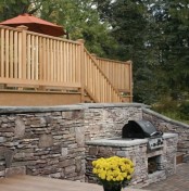 a traditional outdoor bbq zone with a stone wall and bbq countertop plus a grill and a table for eating