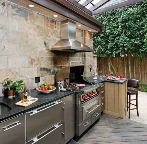 a stylish modern kitchen with metal cabinets, black countertops and a grill plus a hood